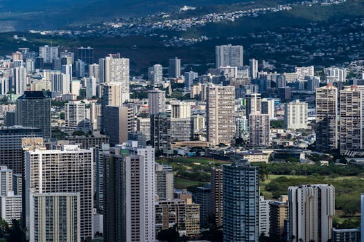 Photo by Cyrill Stunning aerial shot of Honolulu's urban skyline featuring towering skyscrapers and lush surroundings.