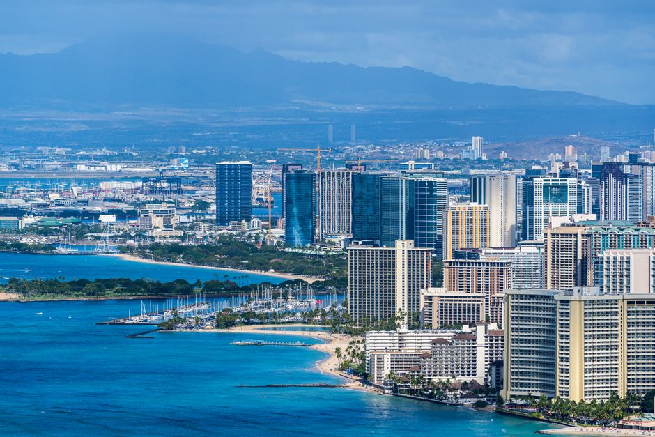Photo by Cyrill Explore this breathtaking aerial view of Honolulu, showcasing its modern skyline and pristine coastline against a mountainous backdrop.