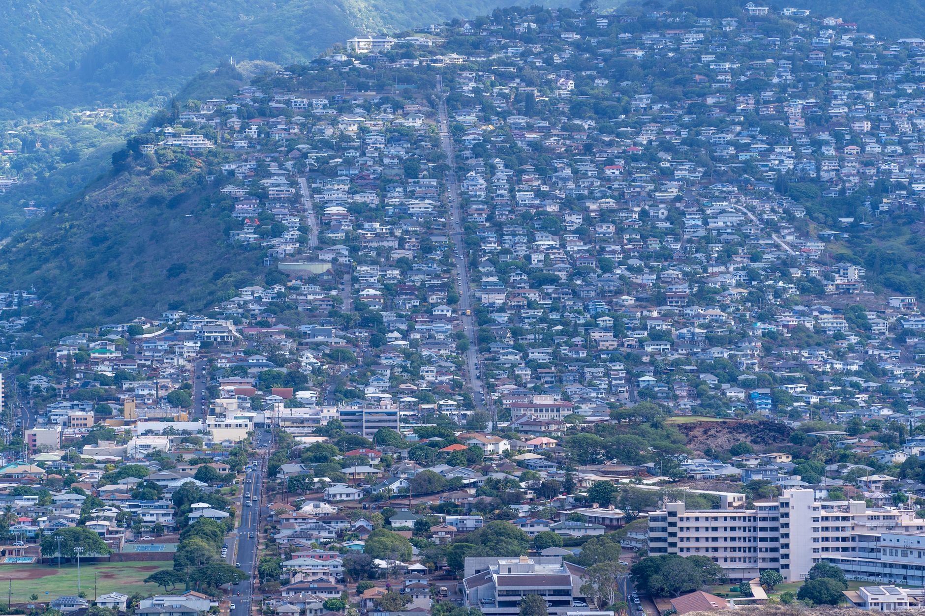 Photo by Cyrill Aerial view of Honolulu's dense urban landscape with hillside residences and lush greenery.