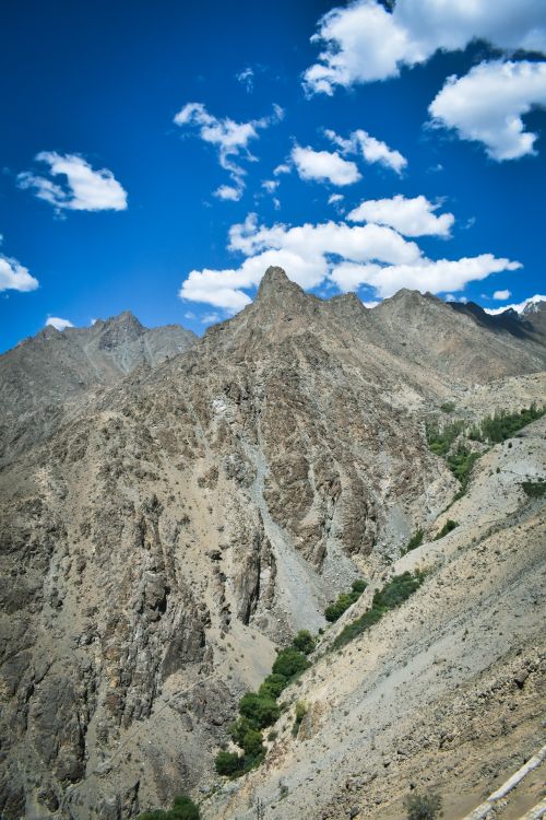 Free Steep rugged mountains with clear blue sky and clouds, perfect for nature and travel photography. Stock Photo