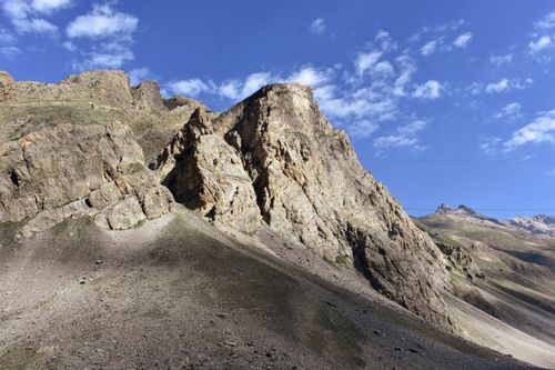 Free A stunning view of rugged mountains under a clear blue sky with scattered clouds. Stock Photo