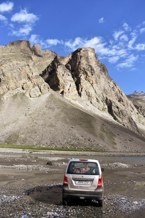 Free SUV car navigating rugged mountain landscape under clear blue sky. Stock Photo