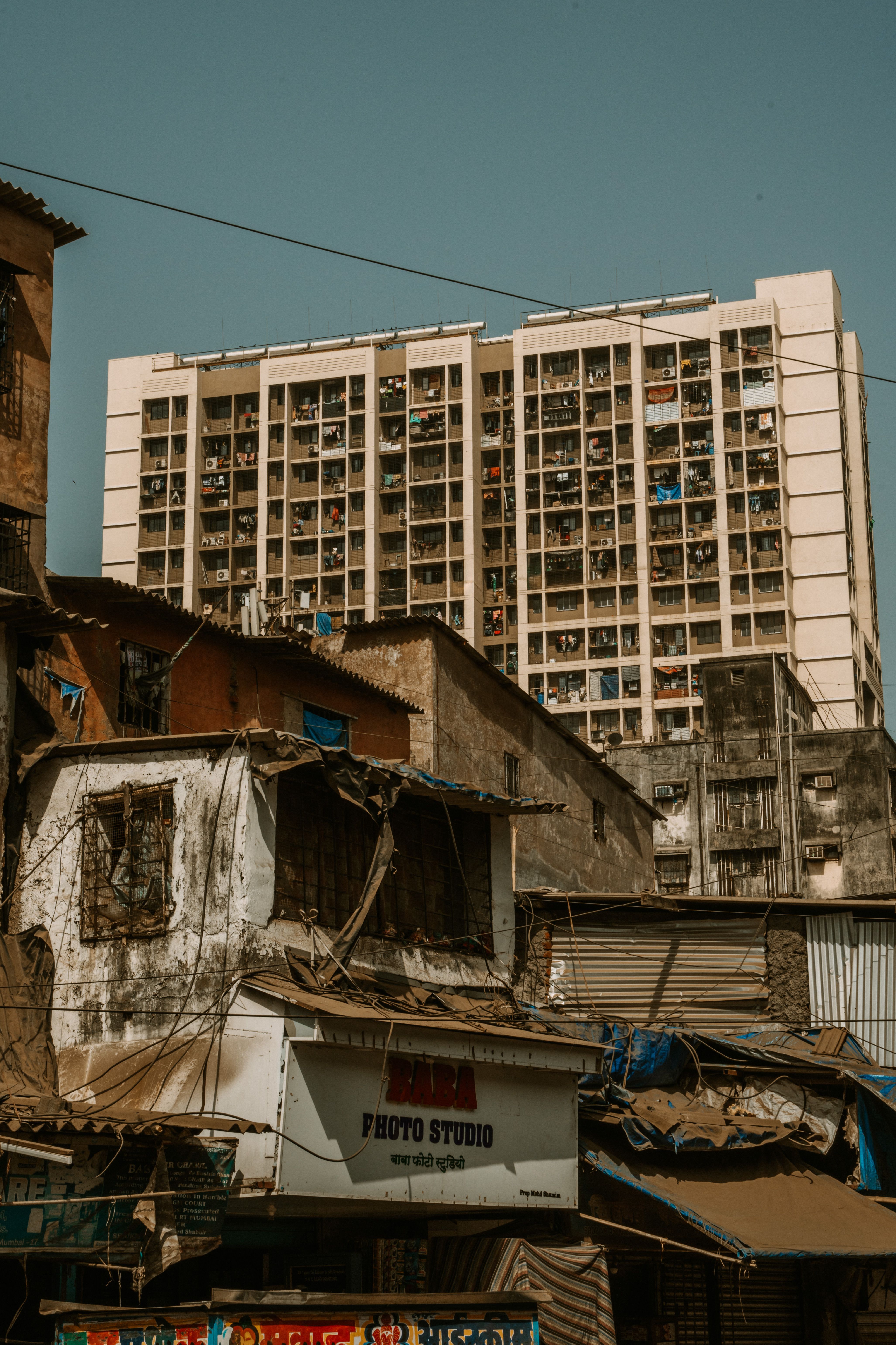 A stark contrast between dilapidated buildings and a modern apartment complex under a clear sky.