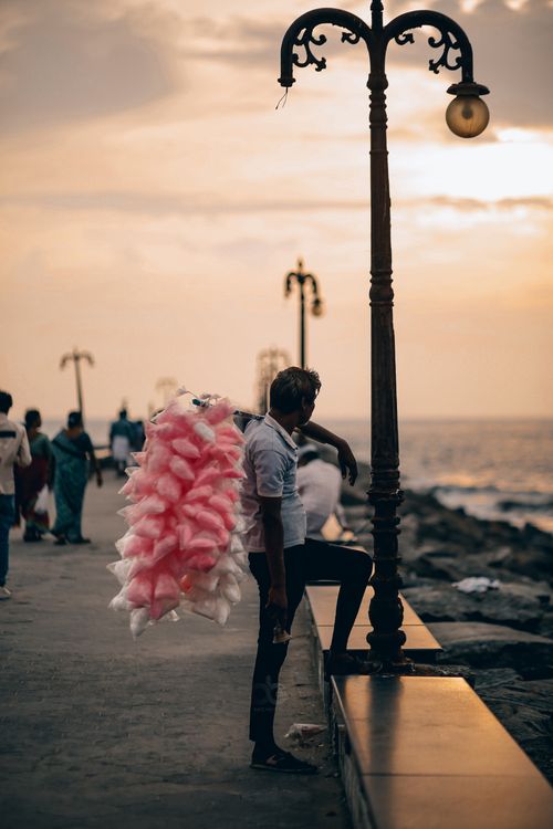 Free A vendor sells cotton candy by the seaside at sunset, creating a serene and nostalgic atmosphere. Stock Photo