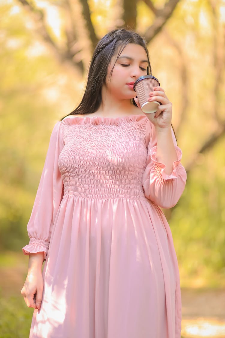 Girl In Dress Drinking Takeaway Coffee In Park