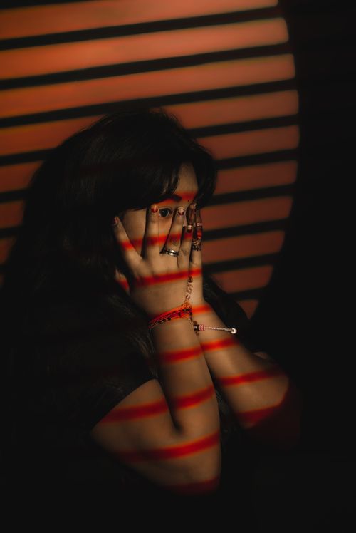 Free Low light artistic portrait of a woman with dramatic red shadows across her face. Stock Photo