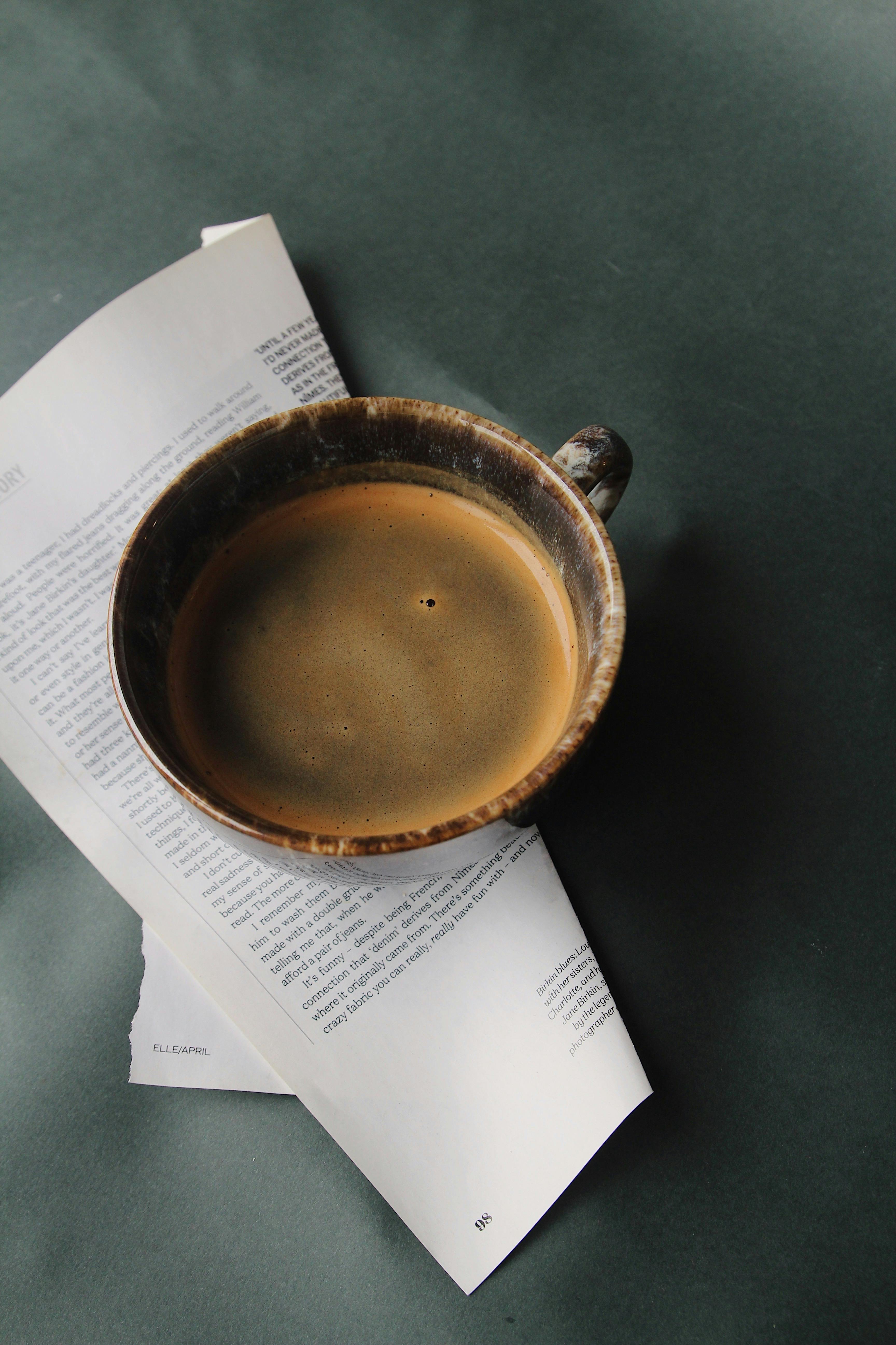 A Woman Sitting on a Bench Holding a Coffee Paper Cup · Free Stock Photo