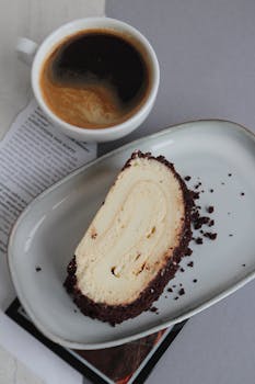 Delicious chocolate cream roll cake served with coffee on a contemporary table setting.