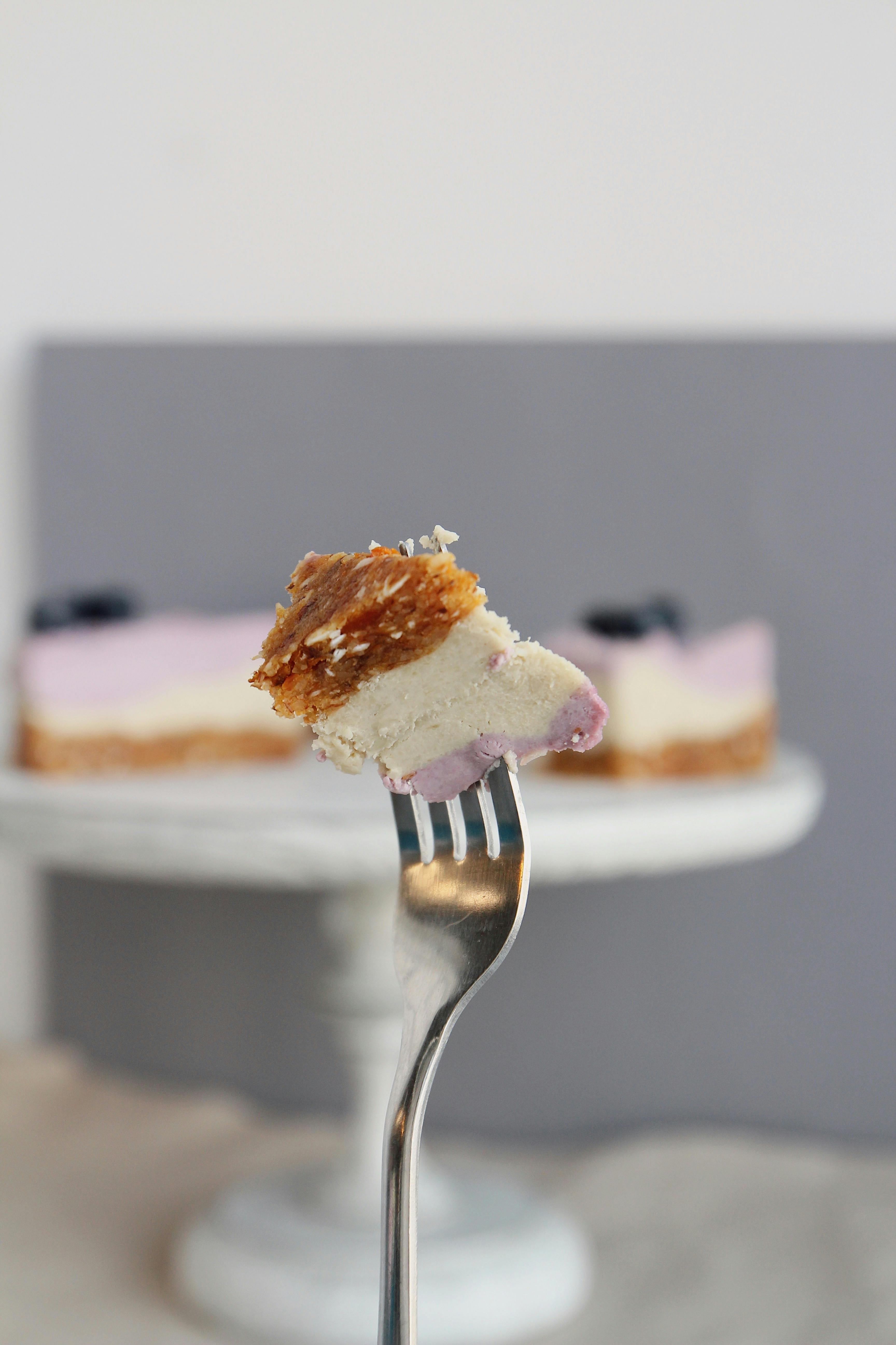 Close-up of a delicious berry cheesecake slice on a fork with creamy layers.