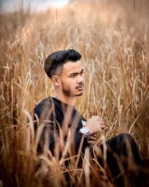 Photo of a Handsome Young Man Sitting in a Field