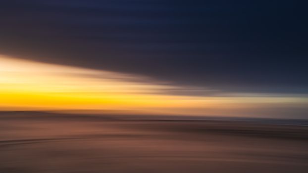 Blurred abstract photo of a sunset over the ocean with impressionist colors and textures.