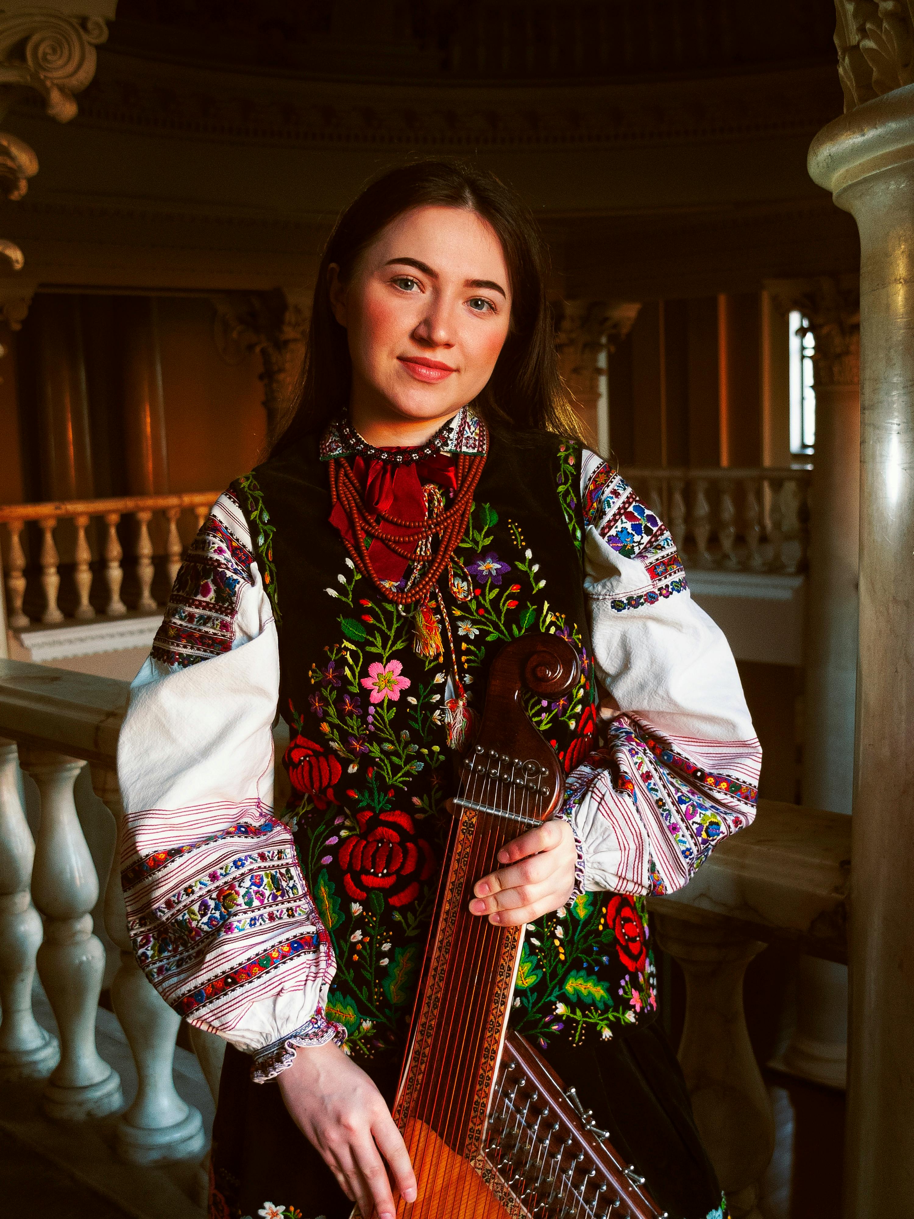 Young woman in vibrant traditional Polish folk clothing with intricate embroidery indoors.