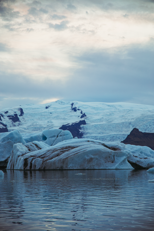 Free Serene Arctic landscape featuring majestic icebergs and calm waters under a dramatic sky. Stock Photo