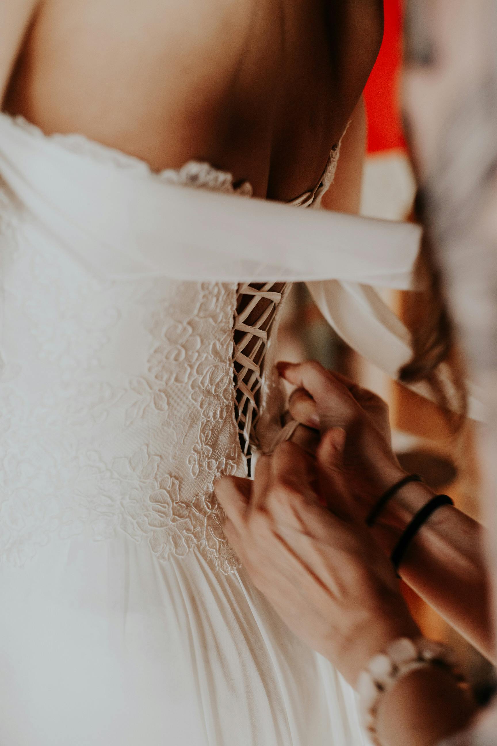 Detailed shot of a bride getting her dress adjusted before the wedding ceremony.
