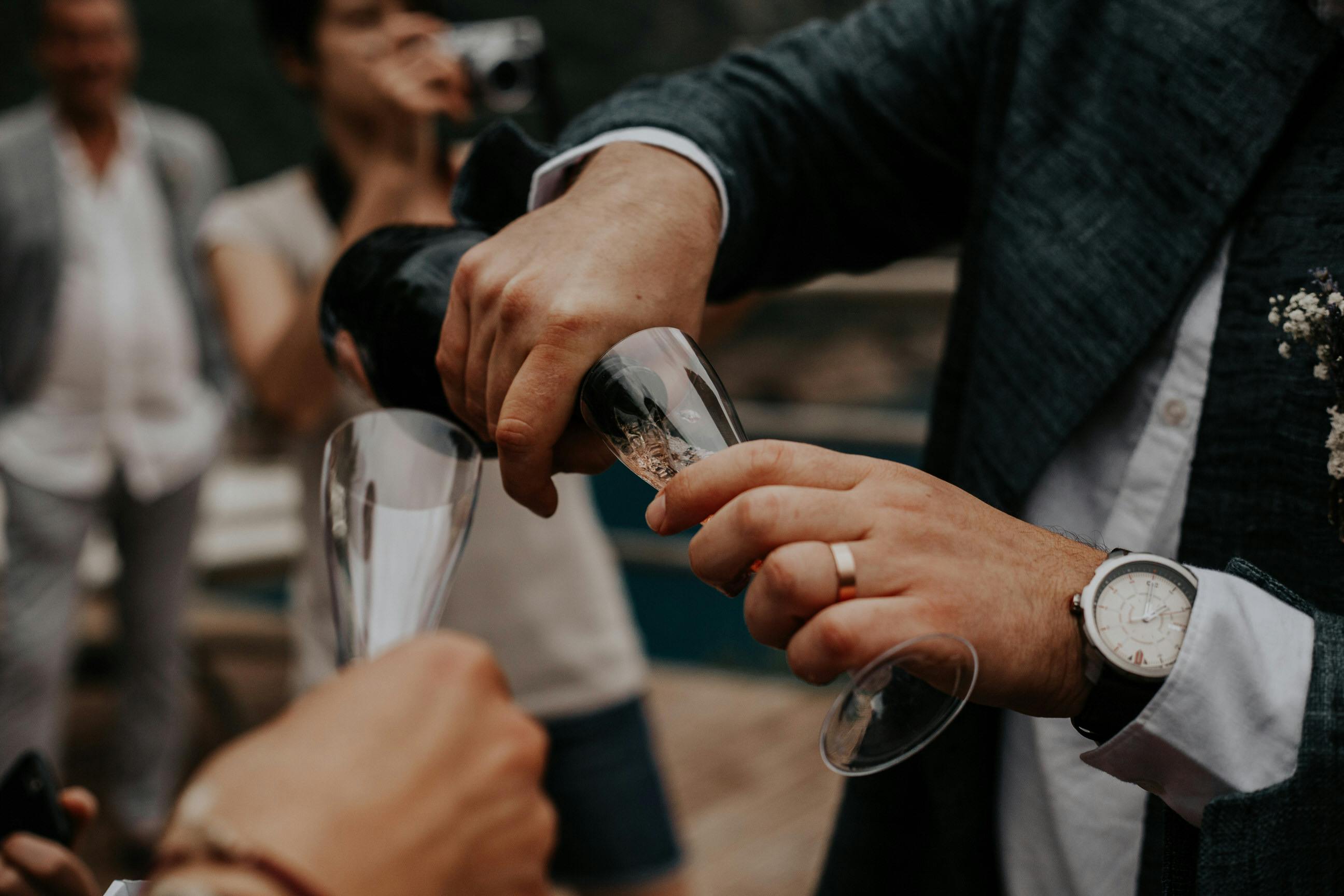 man pouring white wine into a wineglass