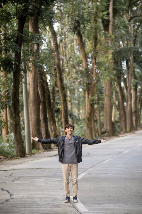 Young Man Standing in the Middle of the Road with his Arms Spread 