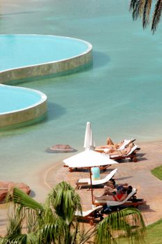 People enjoying leisure and sunbathing by a poolside resort in Agadir, Morocco.