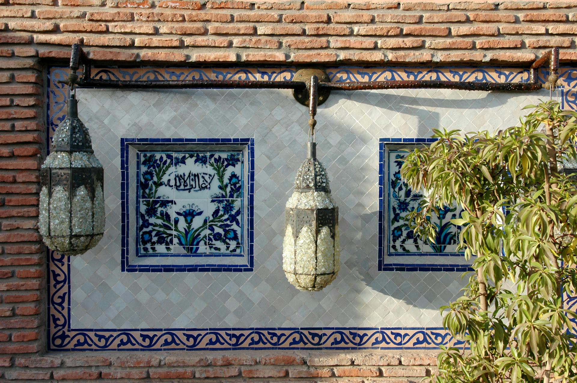 Decorative Moroccan wall with hanging lanterns and intricate tile art in Marrakech.