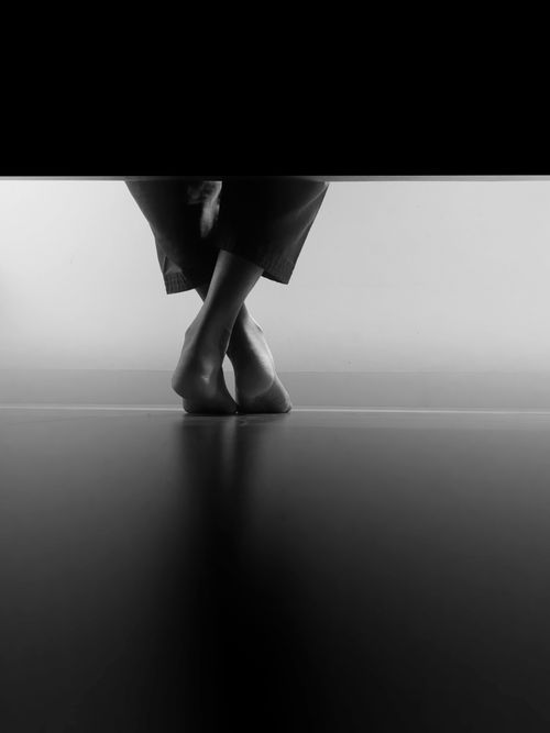 Free Minimalist black and white photo of crossed barefoot legs. Stock Photo