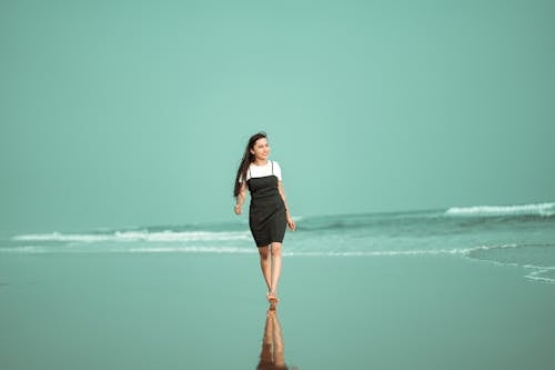 Young Woman in a Dress Walking on the Seashore 