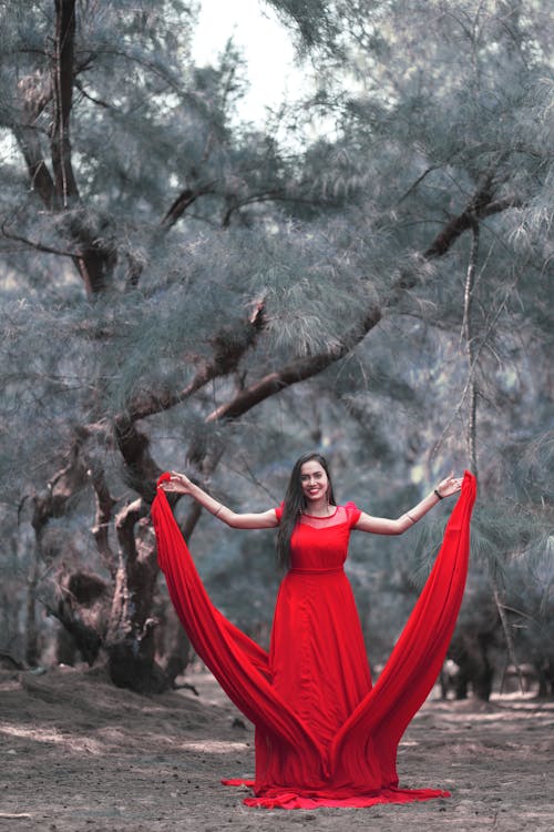 Smiling Woman in Red Dress Posing in Winter Forest