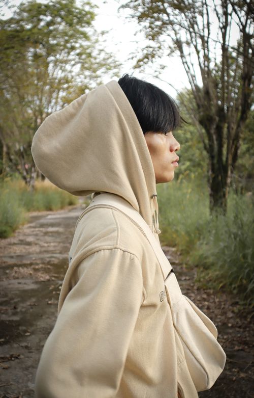 Free Profile of a young woman in a hoodie walking along a forest path, surrounded by trees. Stock Photo