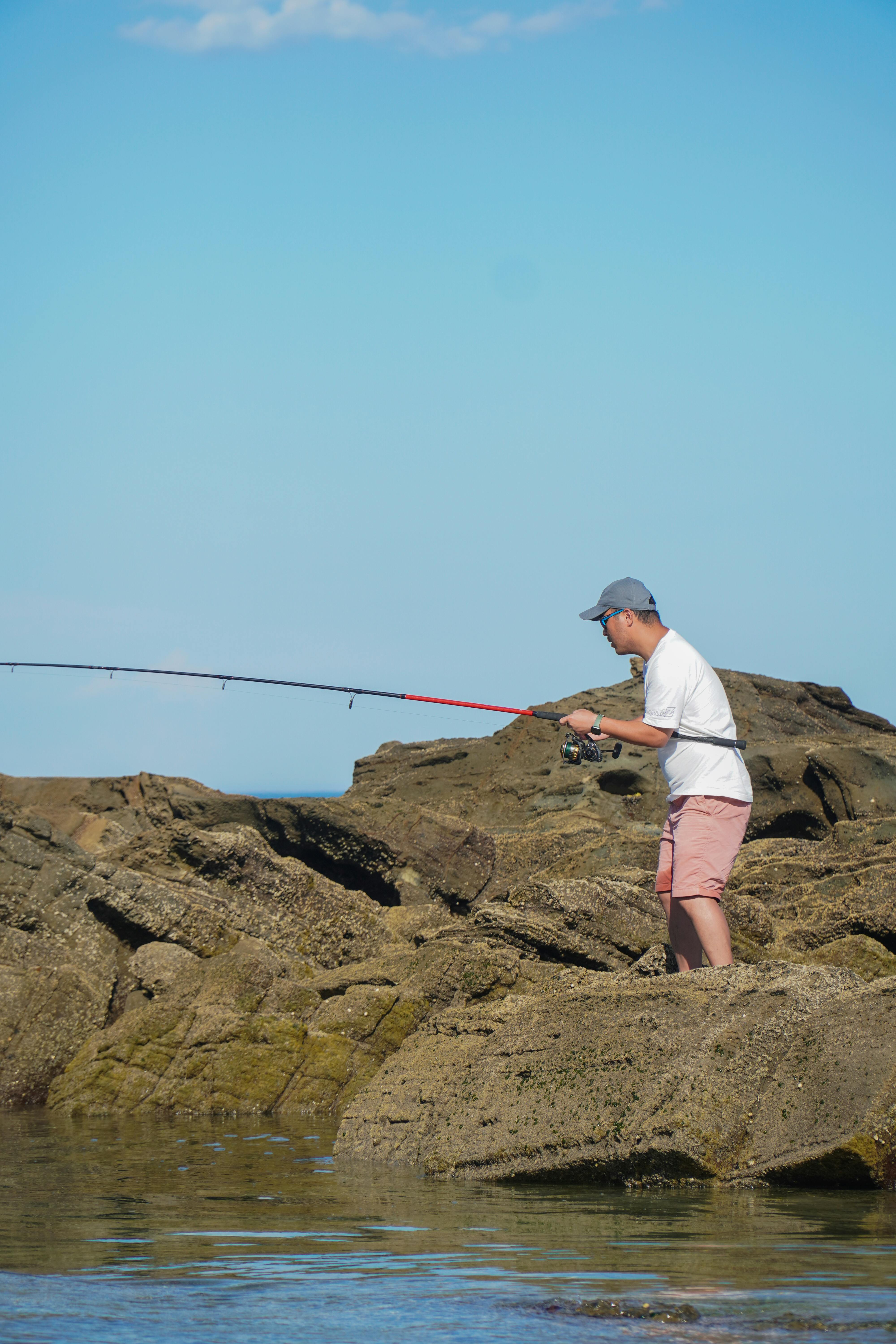 Man with Rod Fishing on Rocks · Free Stock Photo