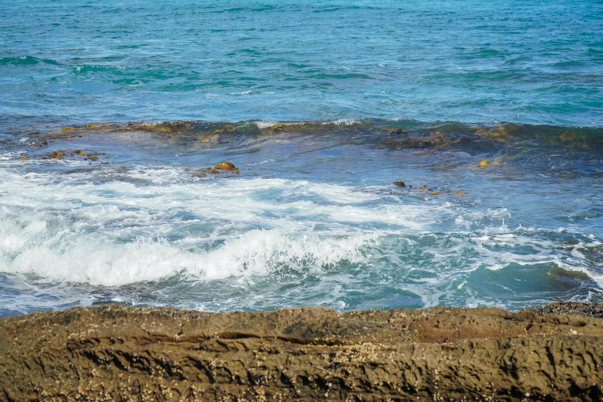 Peaceful ocean waves break over rocky seashore, capturing serene coastal beauty.