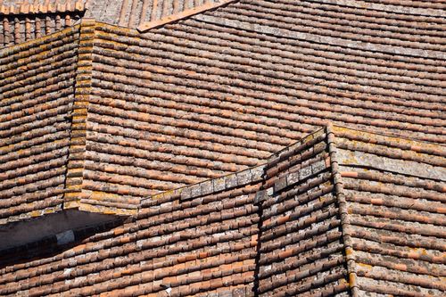 Free Aerial view of weathered terracotta rooftop tiles in a geometric pattern under bright sunlight. Stock Photo