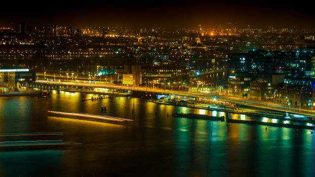 Stunning night view of Amsterdam with illuminated cityscape reflecting on the waterfront.