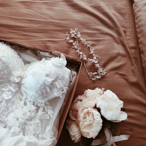Free A beautiful wedding dress with a floral bouquet and accessories on a bed. Stock Photo