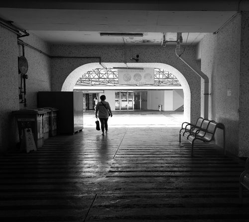 Free A solitary woman walks through an urban train station passage in monochrome. Stock Photo
