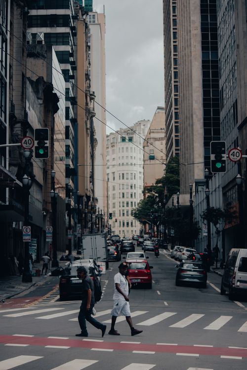 Free A busy city street with cars and pedestrians crossing at a zebra crossing in an urban environment. Stock Photo