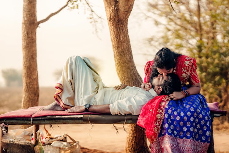 Couple In Traditional Clothes Kissing In Garden