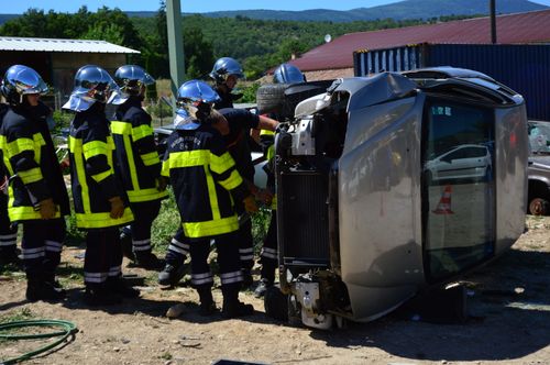 Free Firefighters attending to an overturned vehicle at an accident scene. Daylight outdoor operation. Stock Photo