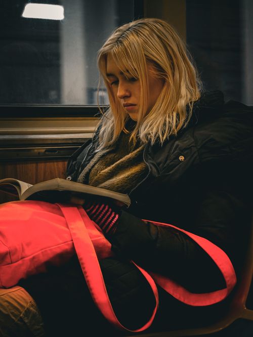 Free Young woman reading while traveling on a train, engrossed in her book. Stock Photo