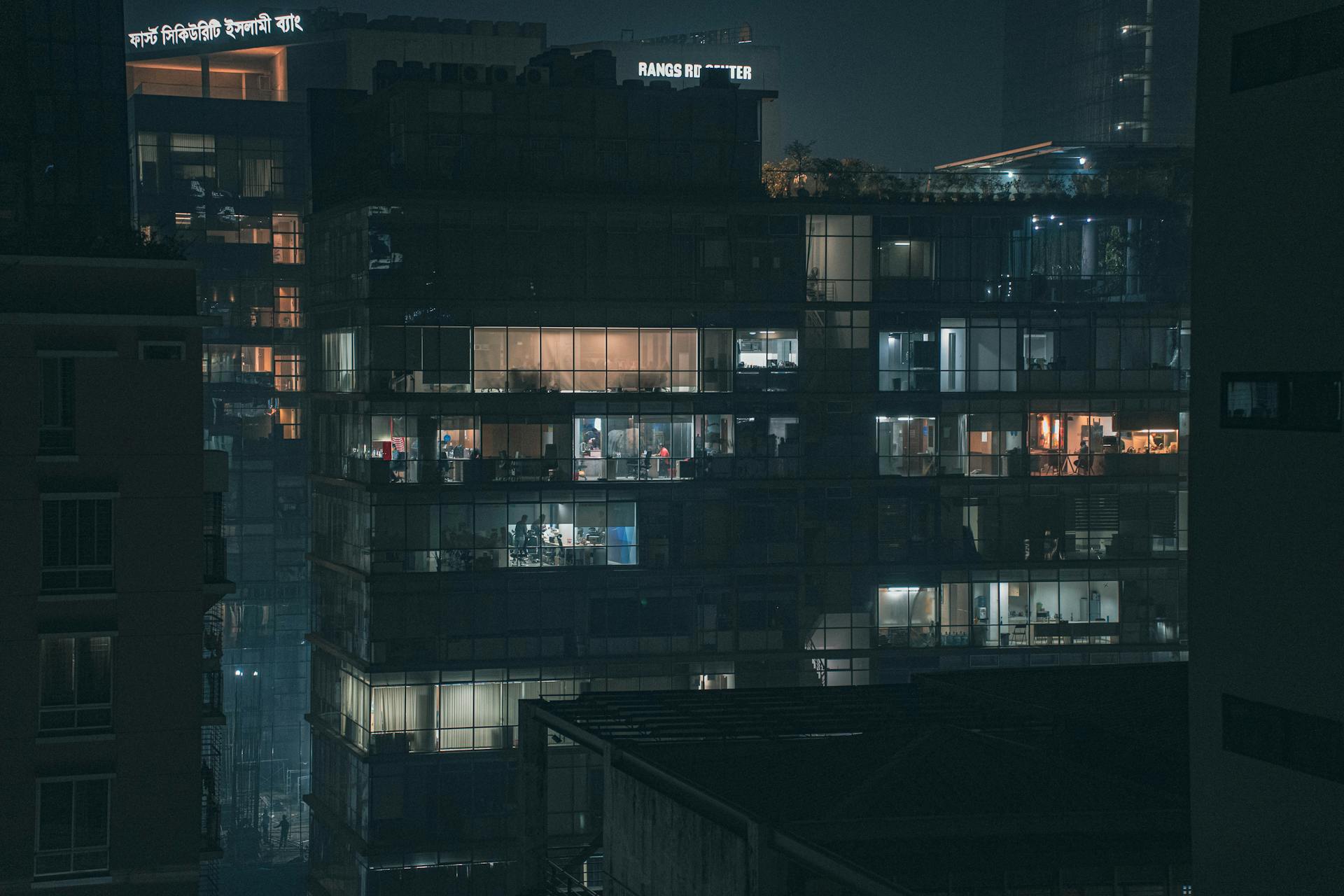 Illuminated office building in Dhaka's cityscape, showcasing modern architecture at night.