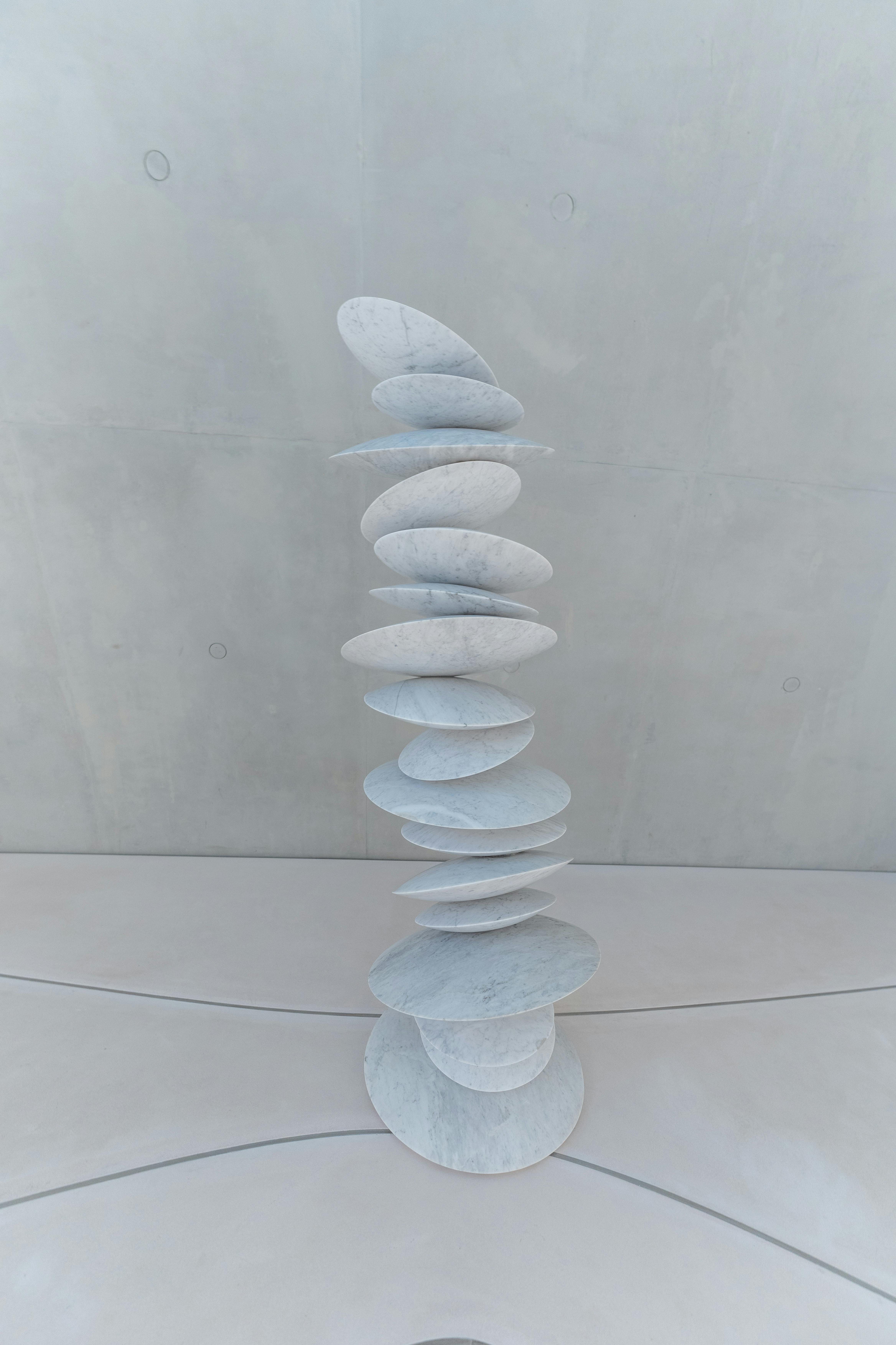 Minimalist white sculpture installation in a modern indoor setting, showcasing artistic balance.