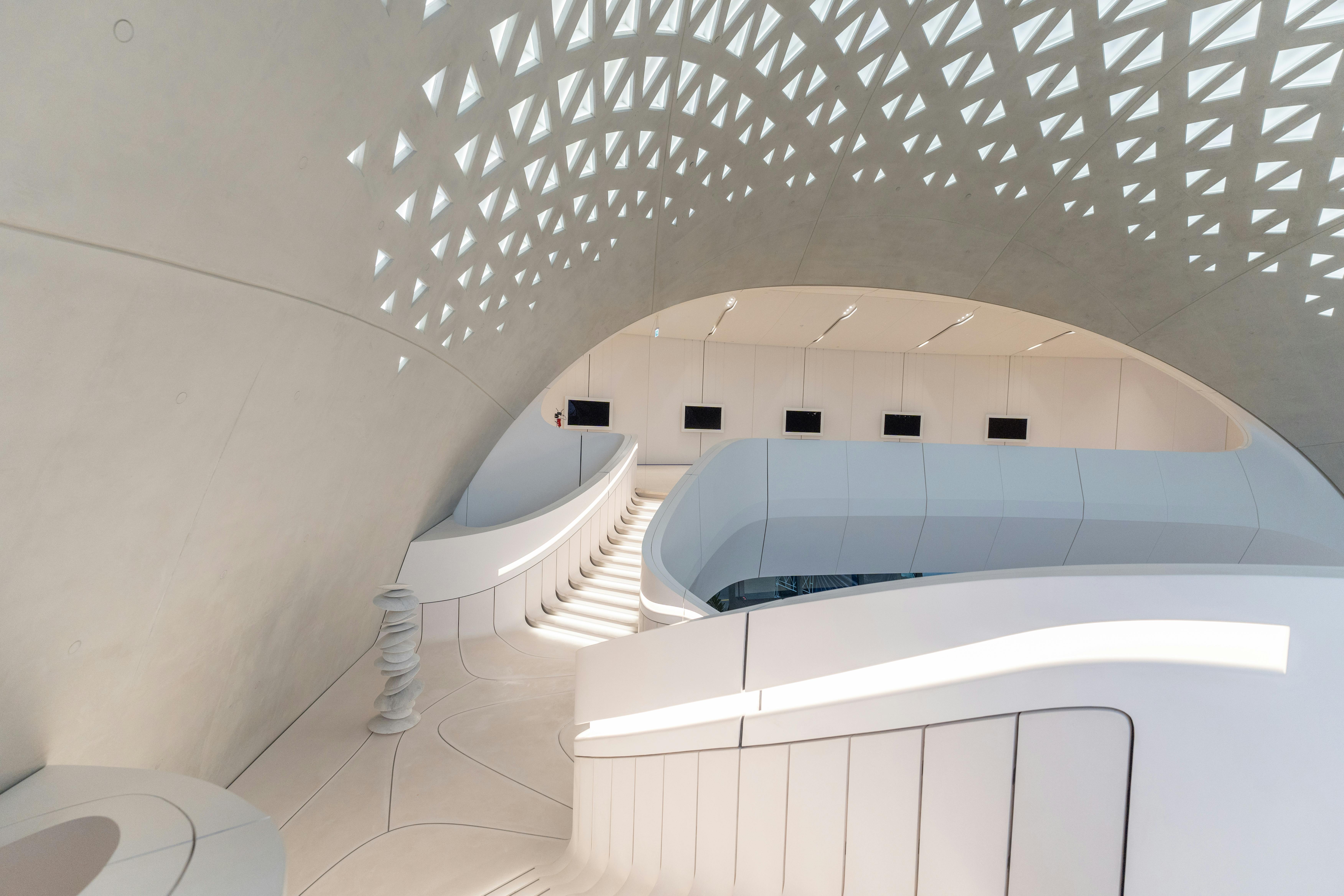 Stylish modern interior featuring a curved staircase and geometric ceiling design, perfect for contemporary architecture lovers.