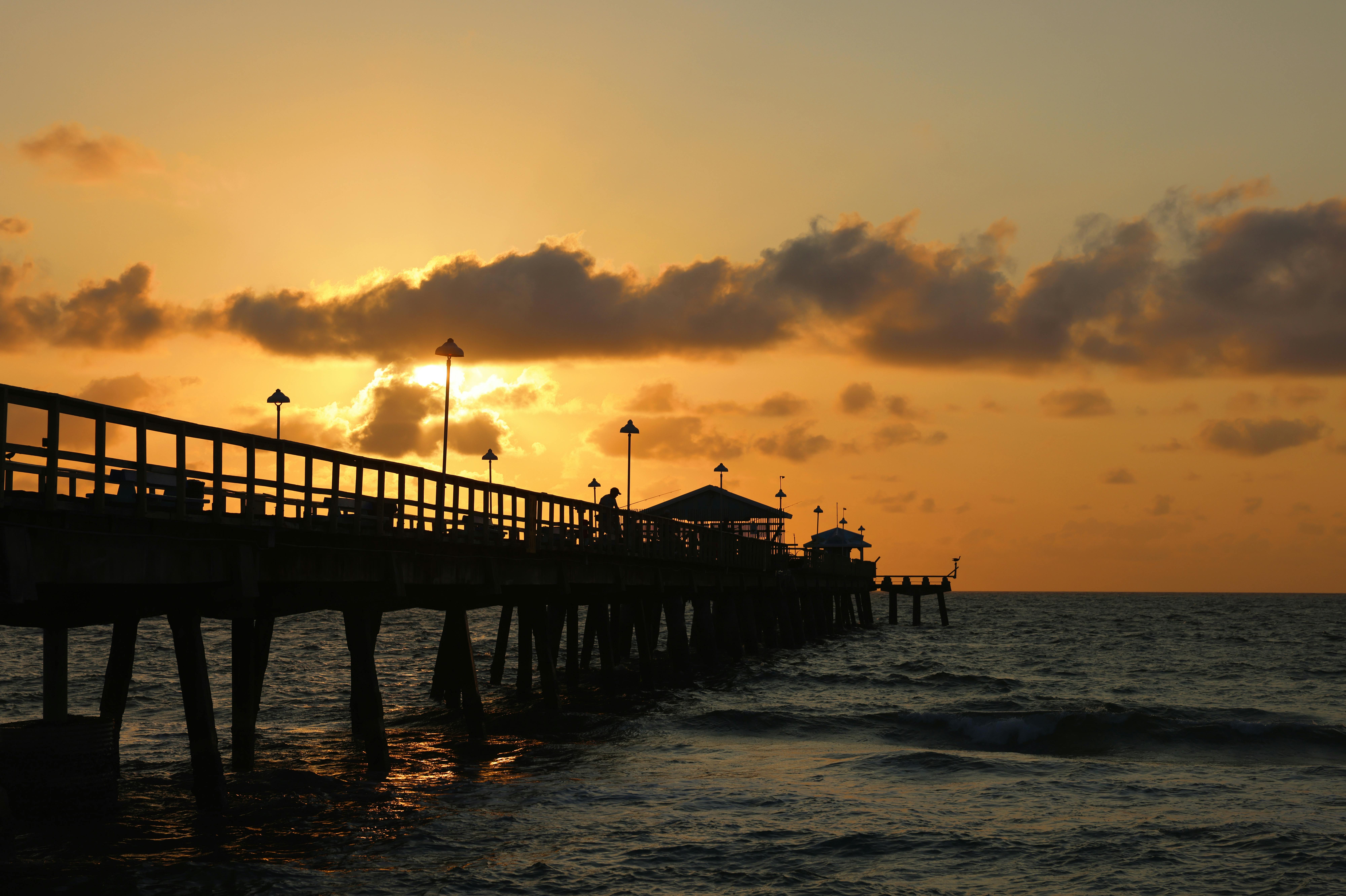 Vibrant sunset view over the ocean at Lauderdale-by-the-Sea pier, creating a serene seascape.