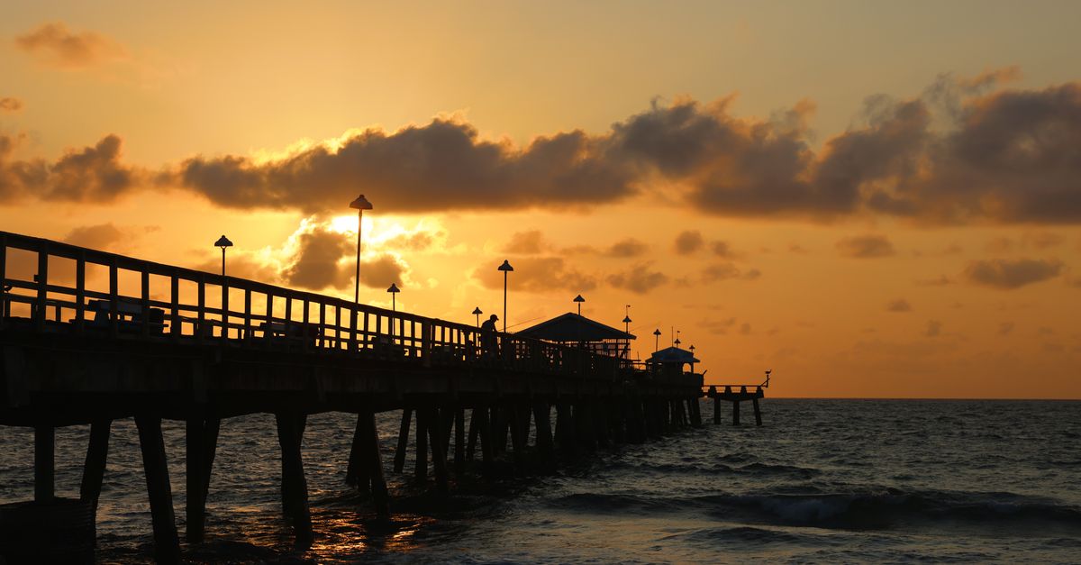 Vibrant sunset view over the ocean at Lauderdale-by-the-Sea pier, creating a serene seascape.