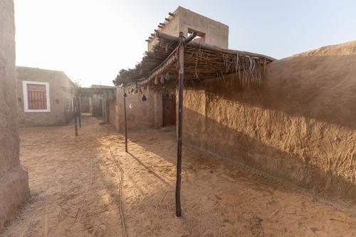 Free A serene view of a traditional desert village with mud houses and sandy pathways at sunset. Stock Photo