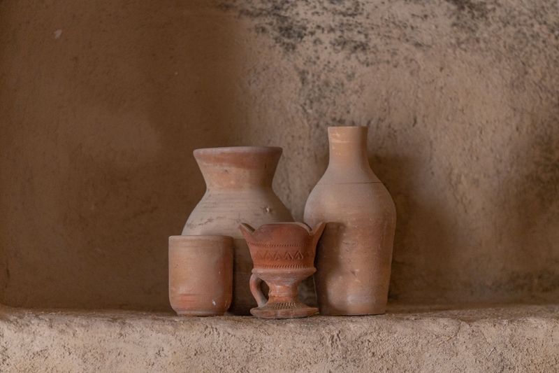 Finished white pots and teapots resting on a wooden studio shelf