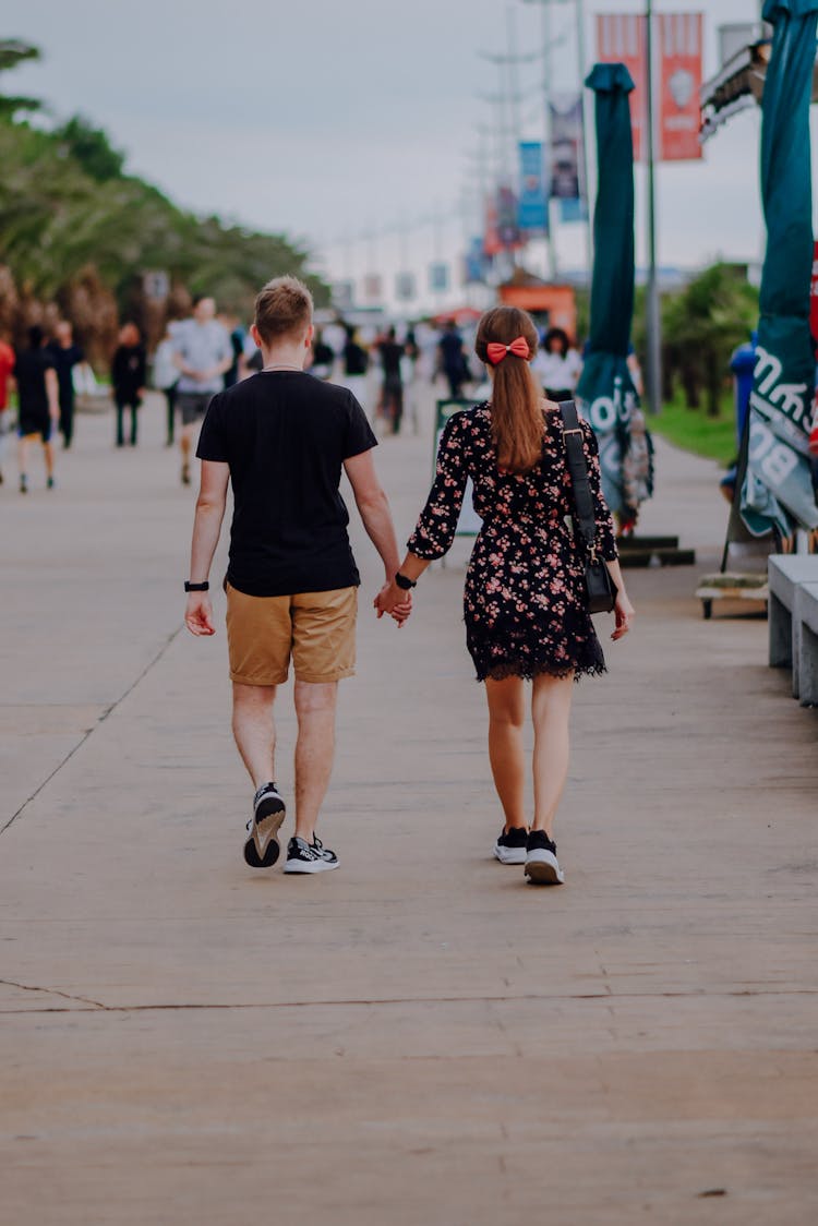 Back View Of A Young Couple Walking On A Sidewalk 