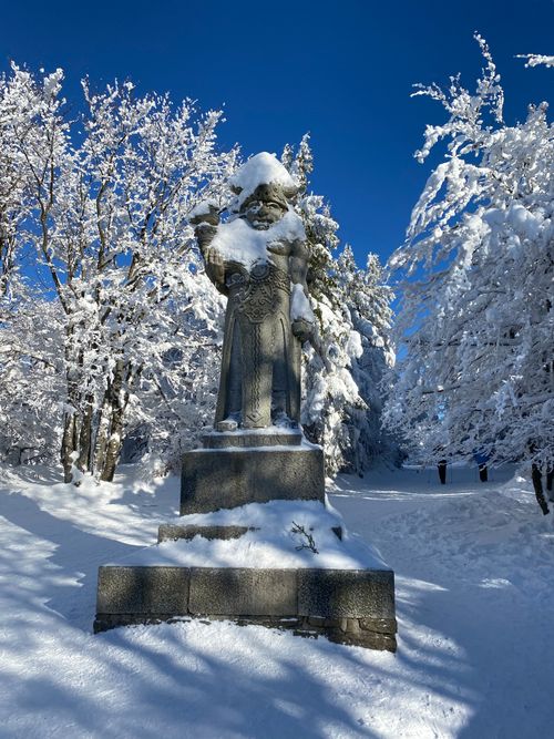 Free A statue in a snow-covered forest depicting a winter scene under a clear blue sky. Stock Photo