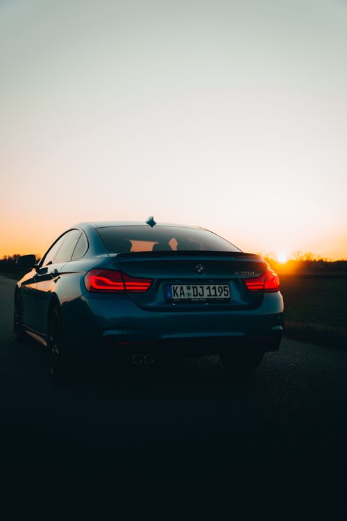 Free A car driving towards the horizon at sunset on a deserted road, creating a serene and picturesque scene. Stock Photo