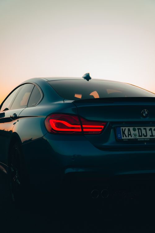 Free A sports car with its taillight illuminated, captured at sunset, showcasing elegance and power. Stock Photo