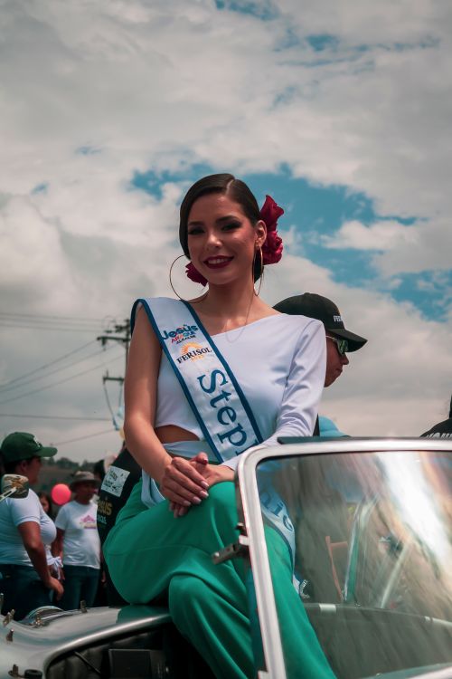 Free A pageant contestant smiles while sitting on a car in Mérida, showcasing vibrant urban culture. Stock Photo