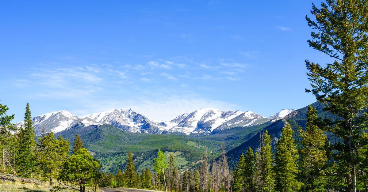 Explore the stunning views of snow-capped Rocky Mountains from a winding road in Estes Park, Colorado.