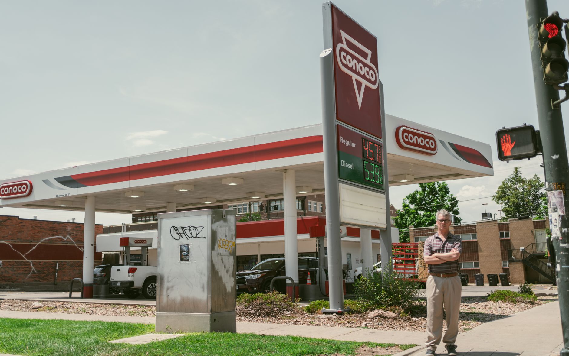 Man standing by a Conoco gas station on a sunny day in Denver, Colorado.